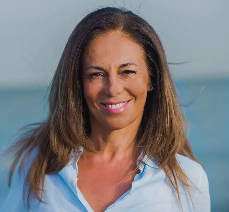 middle age woman smiling and looking at the camera at the beach