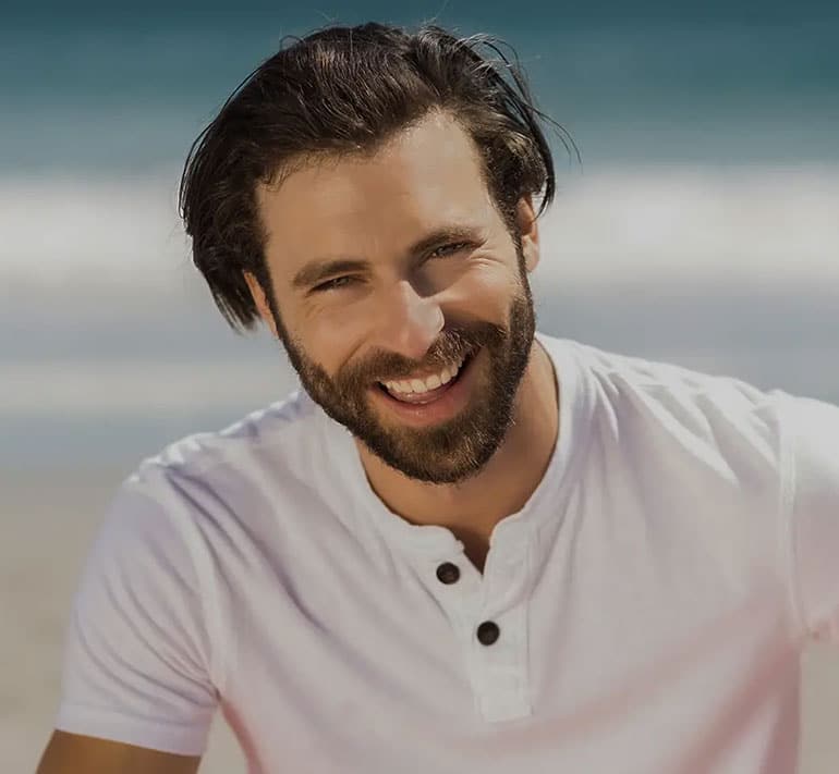 smiling young man wearing a white shirt near the sea