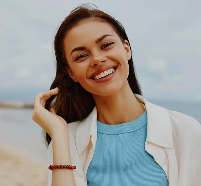 young woman smiling and looking at the camera at the beach