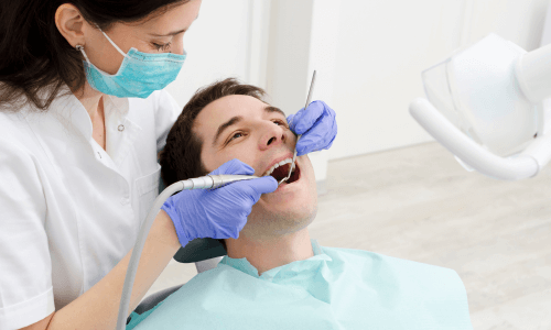 Dentist performing a dental procedure on a male patient Dentist performing a dental procedure on a male patient
