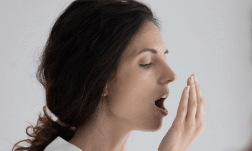 Woman checking her breath by exhaling into her hand. Woman checking her breath by exhaling into her hand.